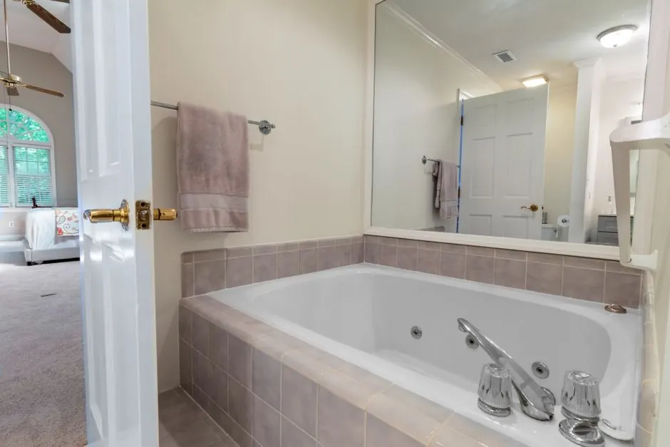 A bright and elegant bathroom featuring a large mirror and bathtub, ideal for relaxation.
